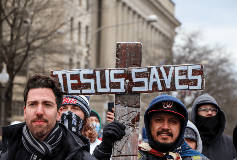 Trump supporters at the Jan. 6 Capitol riot hold a cross that says 'Jesus Saves'