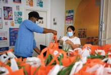 A worker hands a bag of groceries to a woman at La Casa in Mt. Pleasant, Washington, DC.