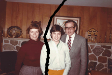 The sepia-toned image shows a family of three standing in front of a fireplace. There is a rip in the image, with the mother on one side and the daughter and father on the other. 