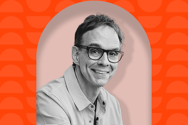 A black-and-white headshot of a white man with large glasses, short hair, and collared shirt overlaid on a light pink outline on top of a dark red background with slightly lighter red half-moon shapes.