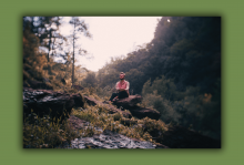 Parker Millsap sits on a rock in the forest.