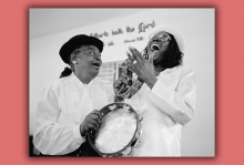 A vintage photo of two Black women laughing and playing instruments in church.