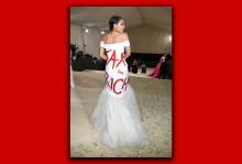 Alexandria Ocasio-Cortez stands with her back to the camera, displaying a ball gown that says "Tax the Rich."